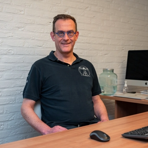 Jo Cosyns zittend aan bureau in zijn praktijk.